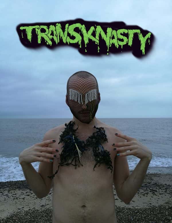  - photo by alum Binks Mooney shows a masculine person standing naked on the beach with the sea behind them with body hair and seaweed on chest and painted nails and a fishnet mask with white string strands covering eyes and the word transknasty in green title above