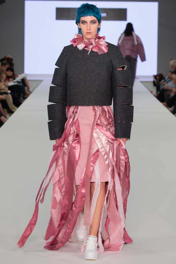Laura Sutton - Image of a model wearing a grey jumper and a pink dress with threaded detail