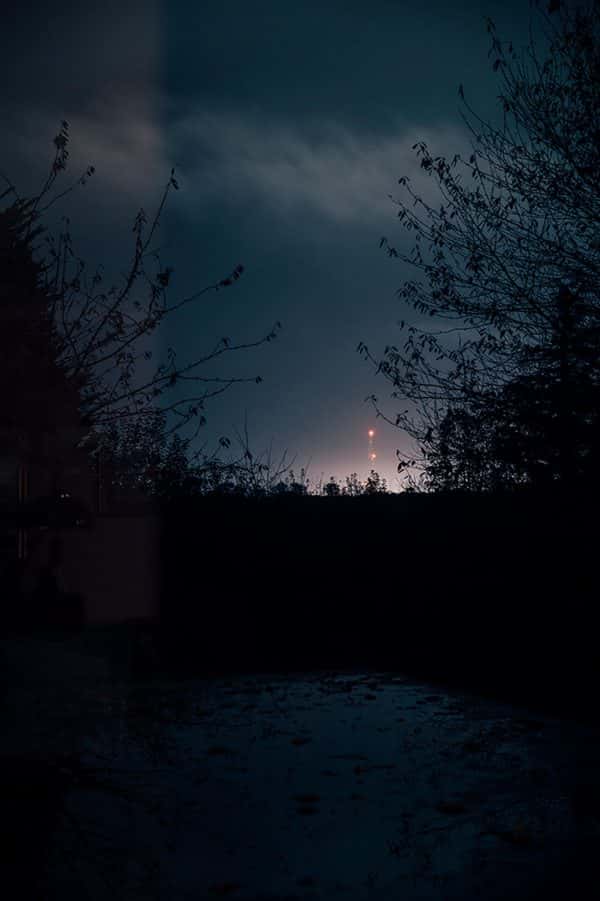 Jeanette Bolton Martin - Shadow skyline photograph shows light on the horizon over a horizon of distant tree tops at night