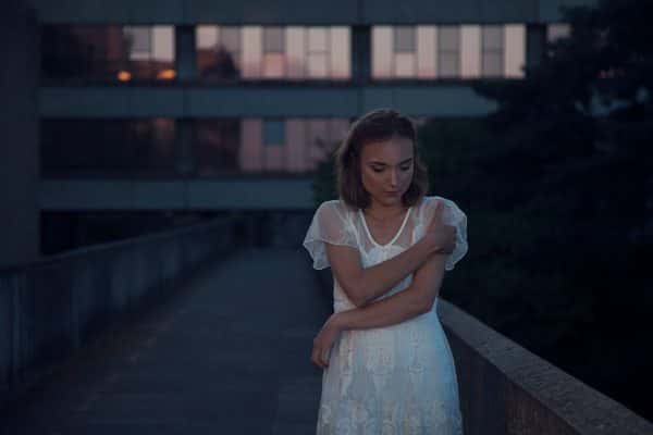 Jensdottir Gudbjorg - Model stands with crossed arms on a concrete walkway at dusk