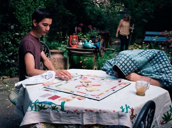 Karim Skalli - children sat around a monopoly board on a table. one hides under a blanket