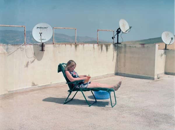 Karim Skalli - Someone sunbathing on a lounger on a roof with high concrete walls