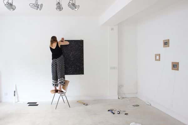 Kate Florence Knowlden - A student mounting their artwork on the wall of the exhibition