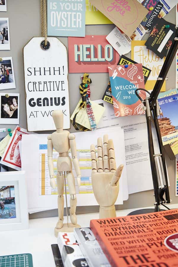 Student room - photo of workspace with magazines in foreground with artist mannequin in centre and several pieces of paper and illustrative typographic images on a board in the background