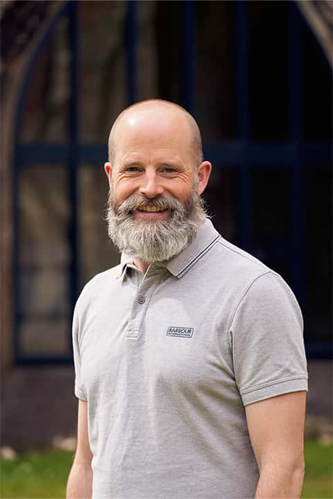 portrait photo of course leader James Smith, with a grey beard and marl grey polo shirt