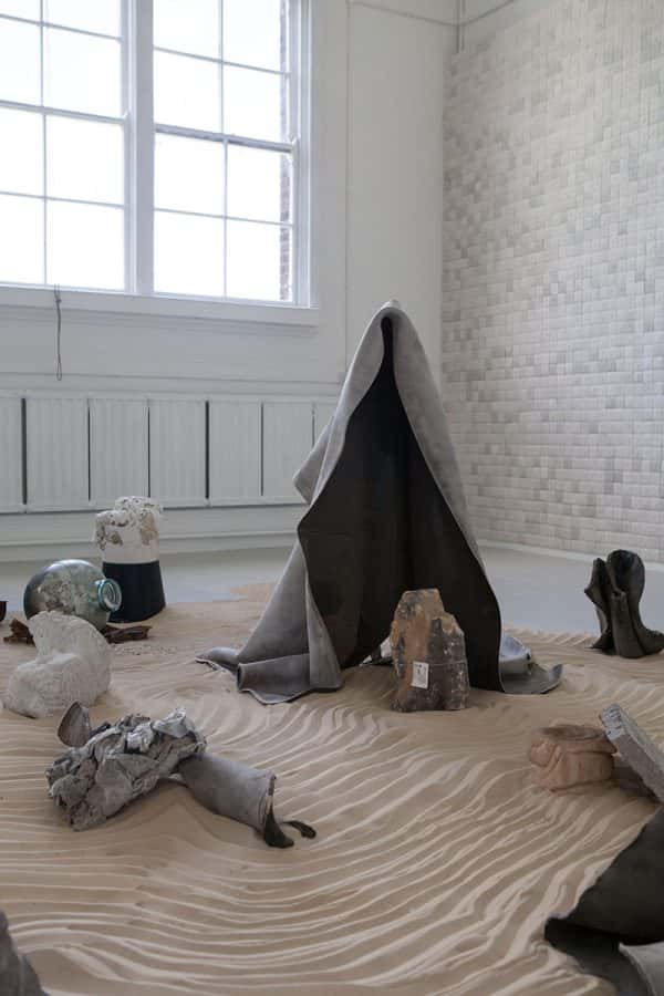 Lindsay Jolly - Fine Art work in the Norwich University of the Arts Degree Show; sand on the floor with objects over it.