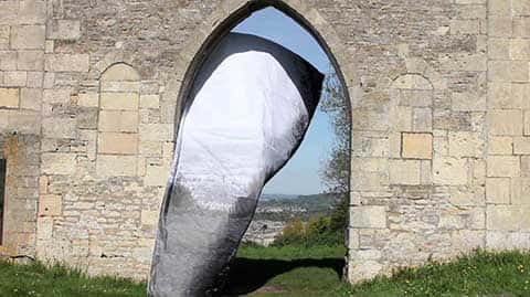 Real Image, installation shot - Installation of a large abstract sculpture in white and pale grey in the archway of a stone wall