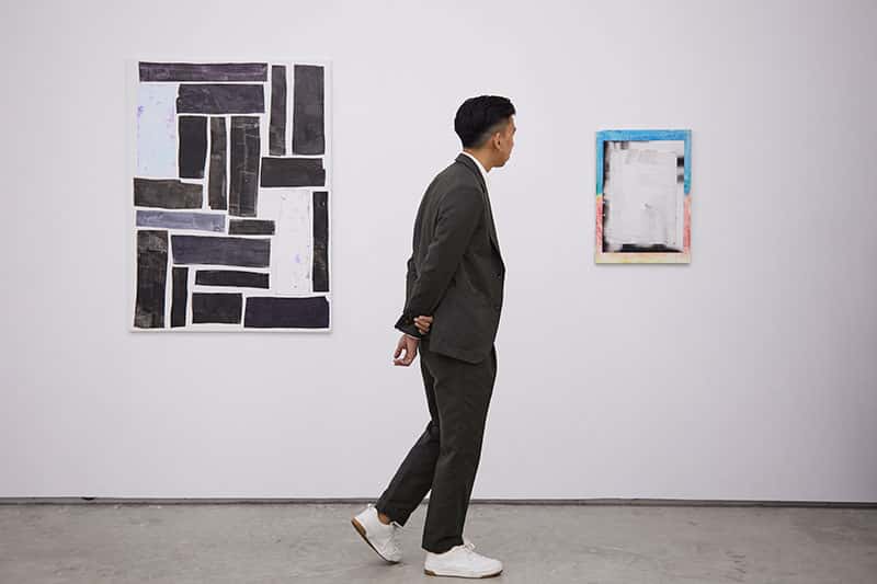 Gabriel Loy, Fine Art graduate walking around his art gallery, 1961 in Singapore looking at 2 paintings