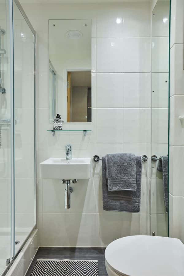 Crown Place bathroom - A clean bathroom with white tiled wall, glass shelf, wall mounted china sink