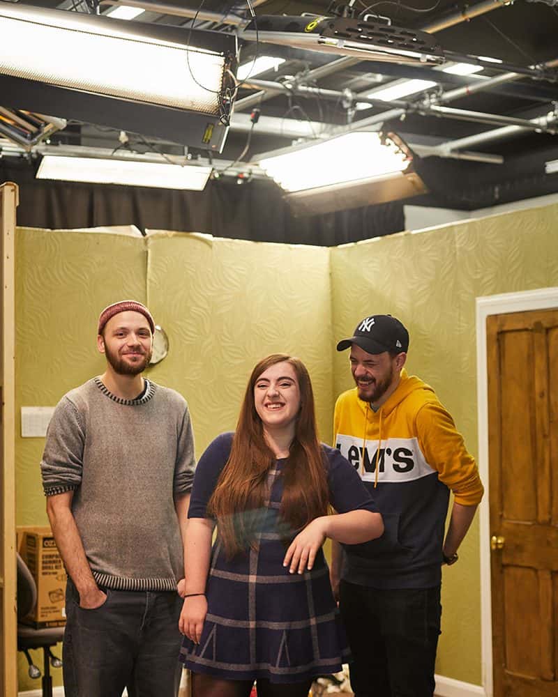 Three students at Norwich University of the Arts stand in the Sir John Hurt film studio