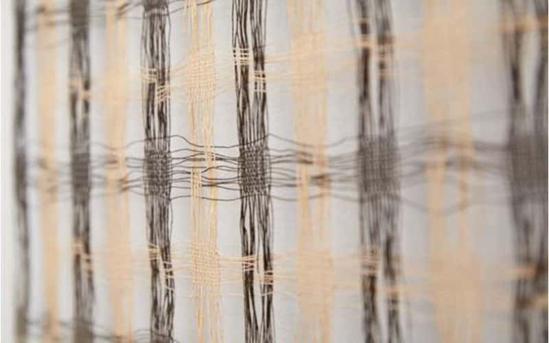 Close up of a checked woven textile piece in pale colours