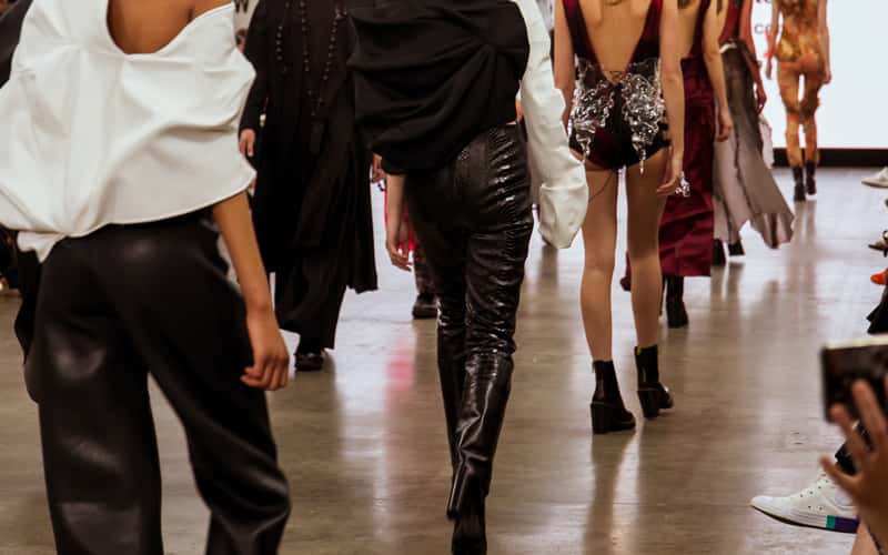 Models walking on a catwalk, wearing BA (Hons) Fashion student garments, at London's Graduate Fashion Week