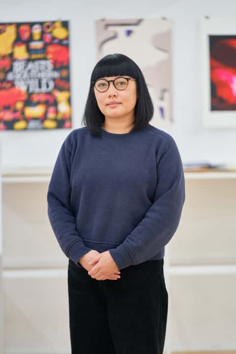 Alice Lee with shoulder length black hair and a fringe, oval rimmed glasses, and a dark blue sweater