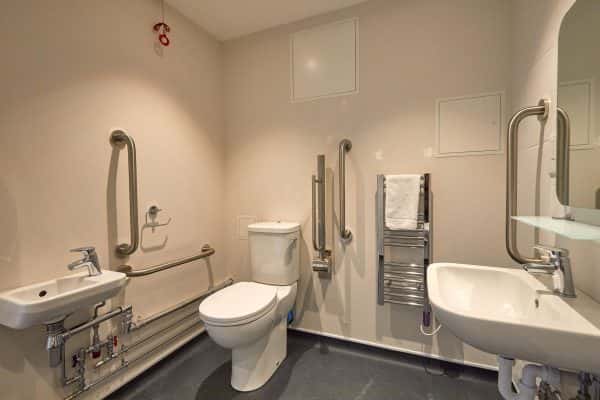 Accessible bathroom - A fully accessible bathroom in Duke St Riverside showing a sink, rails, toilet, towel on radiator and sink with mirror