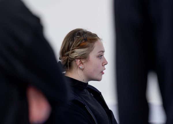  - Side-profile of a student dressed all in black, through the blurred figures of other students, also wearing all black