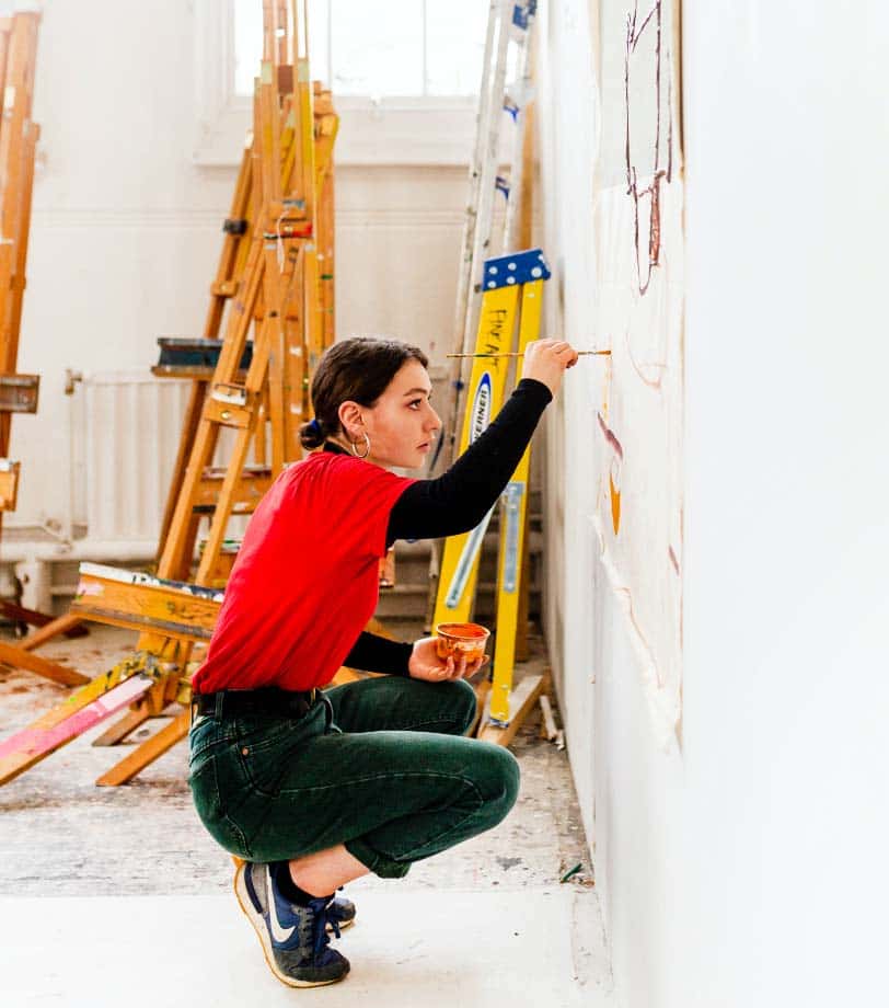 A student paints against the wall in an NUA painting studio