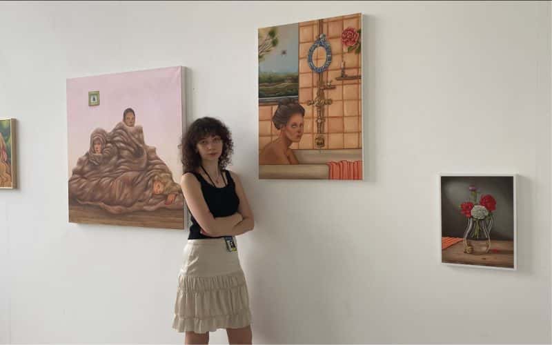 Student standing in front of paintings