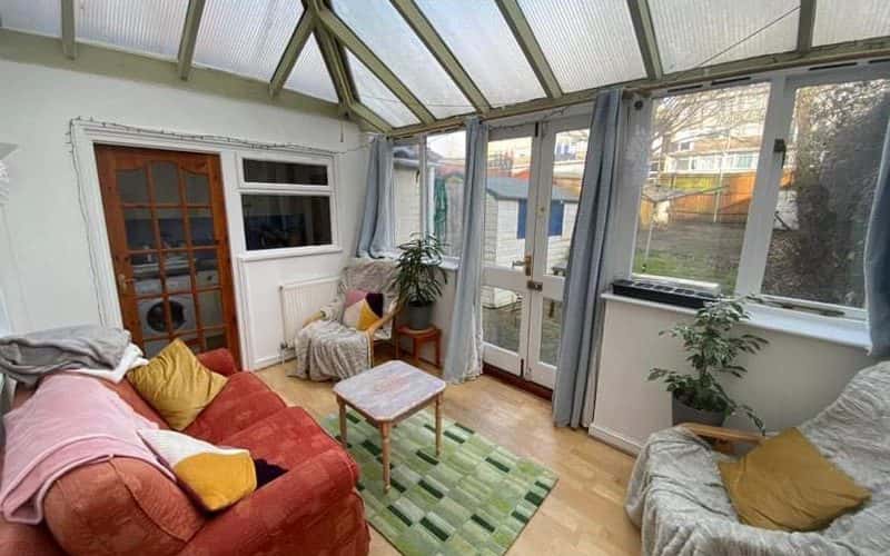 A photo of a shared conservatory in private student accommodation. Two sofas are placed around a coffee table, overlooking the garden.