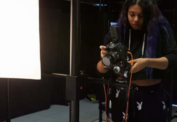  - A photography student lines up a camera which is mounted on a sturdy metal pivot in the photography studio