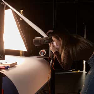 A student leans in with a DSLR to shoot their project in the animation studio
