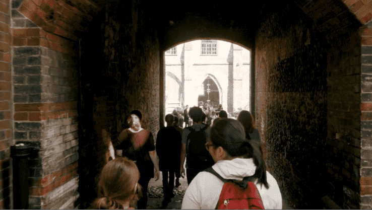 Students walk under a large brick archway in one the NUA Garth buildings near the Monastery