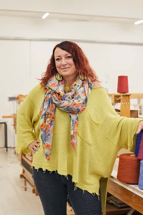 Portrait image of Lindsey Chambers, Director of Fashion & Textiles at Norwich University of the Arts. Lindsey is wearing a batwing sleeve cardigan under a loosely tied floral neck scarf