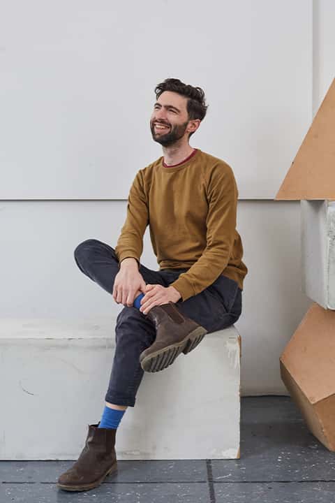 Senior Fine Art Lecturer Ben Mc Donnell sitting on a concrete block in a studio
