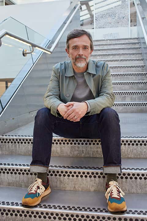 Senior lecturer Andrew Johnson sits on the metal stairs of the Guntons building at Norwich University of the Arts
